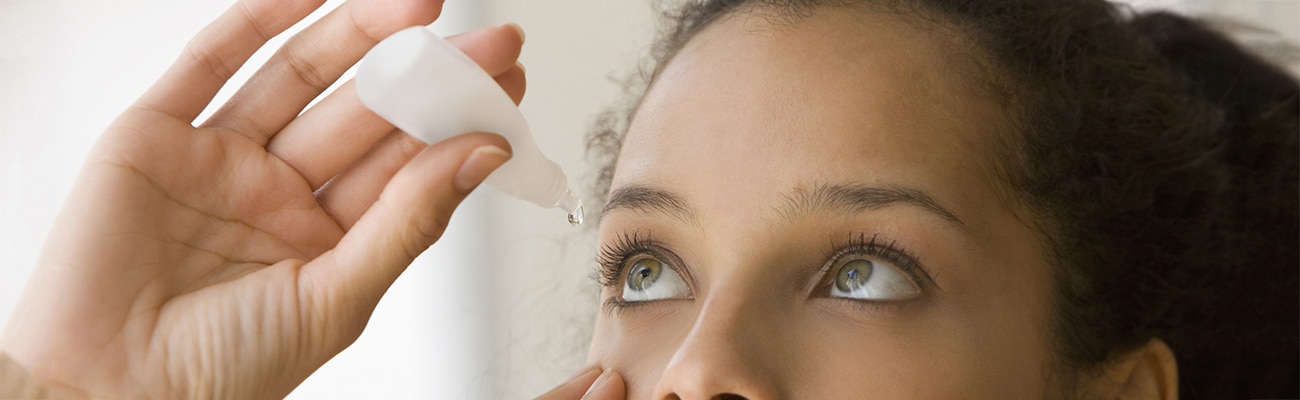 Woman pouring eye drops to treat dry eyes