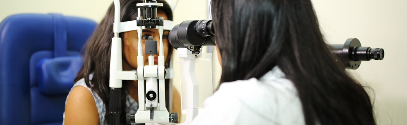 An eye doctor performing an eye exam on a female patient.