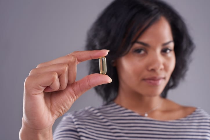 Woman holding fish oil pills to use as treatment for dry eye