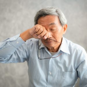 elderly man with glaucoma rubbing his eyes