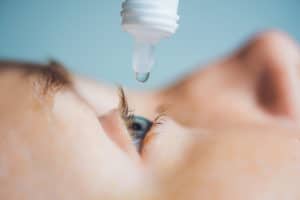 Closeup of eyedropper putting liquid into open eye.