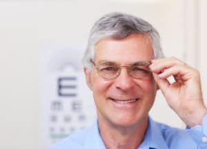 A happy patient showing off his new spectacles while standing in an optometrist's office