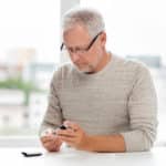 senior man with glucometer checking blood sugar level at home